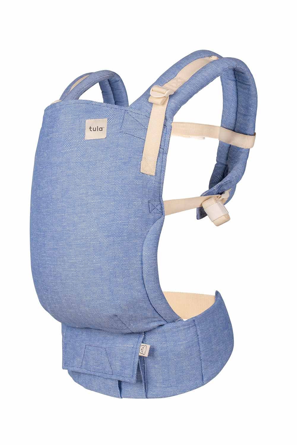 Tula Free-to-Grow baby carrier in a soft blue herringbone fabric with beige straps, featuring an adjustable waistband and padded shoulder straps for comfortable babywearing.