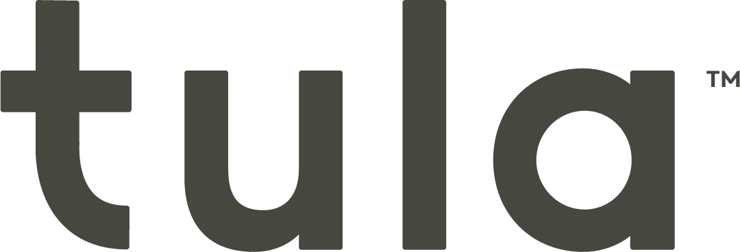 Tula Baby Carrier Review: My Honest Experience and Favorites 1 Mother wearing her baby in a light pink Tula Explore Baby Carrier, holding the child close in a front carry. A “Parents Best for Baby 2025” award badge appears beside her, highlighting the carrier’s recognition for comfort and design.