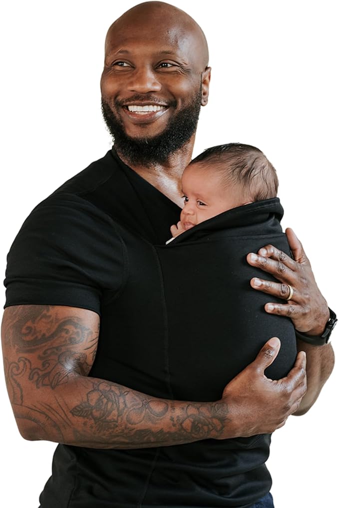 Babywearing 101 - What I Wish I Knew as a First-Time Mom 2 Smiling father holding his newborn close in a soft black baby carrier shirt for dads. The photo highlights safe, hands-free babywearing with skin-to-skin contact, showing how baby carriers for men provide comfort, bonding, and support for both baby and parent.